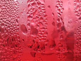 Drops of ice on a red cold drink glass photo