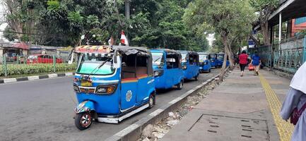 View of activity Bajaj parked on the side of the road around Senen market station waiting for passengers. Jakarta, Indonesia - June 8 2024 photo