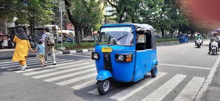 View of activity Bajaj parked on the side of the road around Senen market station waiting for passengers. Jakarta, Indonesia - June 8 2024 photo