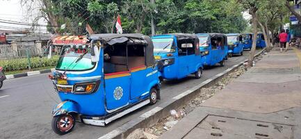 View of activity Bajaj parked on the side of the road around Senen market station waiting for passengers. Jakarta, Indonesia - June 8 2024 photo