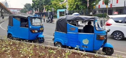 View of activity Bajaj parked on the side of the road around Senen market station waiting for passengers. Jakarta, Indonesia - June 8 2024 photo
