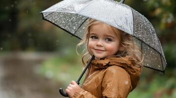 Child enjoys the rain while holding a clear umbrella in a lush, green environment photo