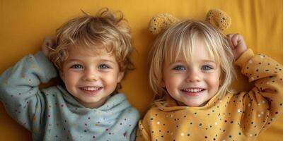 Two joyful kids in colorful sweaters, relaxing and smiling on a vibrant yellow background photo