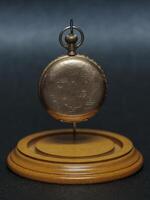 old pocket watch a family heirloom from several generations ago hanging in its display case with out the dome photo