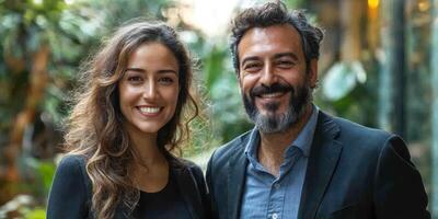 A cheerful couple stands side by side, surrounded by lush greenery in an urban environment photo
