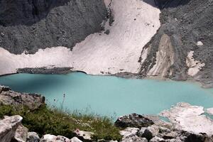 Crystalclear Turquoise Glacier Lake nestled in Rocky Mountain Terrain with patches of snow. Serene untouched nature of the reservoirs on a sunny day while traveling for Posters or Prints photo