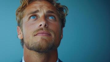 A young man gazes upward, reflecting with a thoughtful expression in a blue setting photo