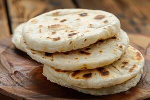 Stack of Four Golden Brown Flatbreads on Wooden Surface photo