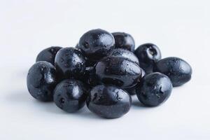 Pile of Dark Blue Plums with Water Droplets on White Background photo