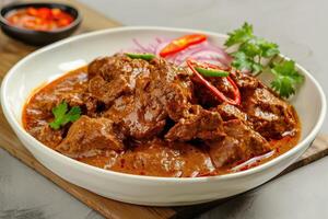A Bowl of Spicy Beef Curry with Red Onions and Chili Peppers photo