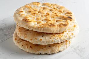 Three Golden Brown Flatbreads Stacked on a Marble Surface photo