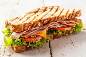 Grilled Turkey, Tomato, and Lettuce Sandwich on a White Wooden Surface photo