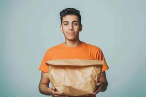 Young Man Holding a Brown Paper Bag in Front of a Light Blue Background photo