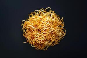 A Pile of Cooked Yellow Noodles on a Black Surface photo