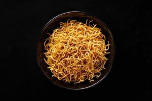 Crispy Noodles in a Black Bowl on a Dark Background photo
