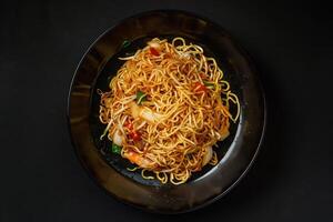 Stir-Fried Noodles with Vegetables and Shrimp on a Black Plate photo