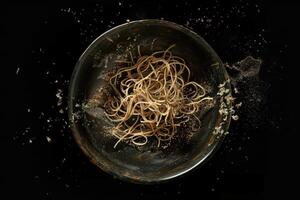 A Bowl of Spaghetti with Golden Specks Against a Black Background photo