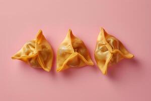 Three Golden Dumplings on Pink Background photo