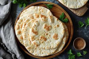 Close-up of Four Golden Brown Pita Breads on Wooden Plate photo