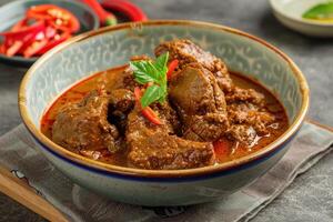 Spicy Beef Curry in a Bowl with Chili Peppers and Basil photo