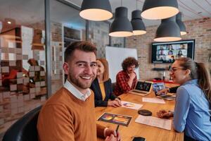 In the vibrant ambiance of a modern startup office, a diverse team of business professionals engage in discussions on various projects and develop new business strategies, epitomizing creativity and photo