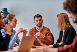 In the vibrant ambiance of a modern startup office, a diverse team of business professionals engage in discussions on various projects and develop new business strategies, epitomizing creativity and photo