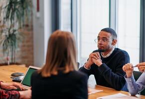 In the vibrant ambiance of a modern startup office, a diverse team of business professionals engage in discussions on various projects and develop new business strategies, epitomizing creativity and photo