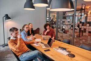 In the vibrant ambiance of a modern startup office, a diverse team of business professionals engage in discussions on various projects and develop new business strategies, epitomizing creativity and photo