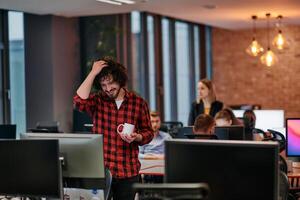 Focused Professional. Interesting Man with Coffee Cup in Office Surrounded by Computers. photo