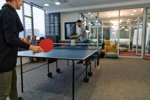 Business colleagues take a break from work to enjoy a game of table tennis, fostering teamwork and camaraderie in the workplace photo