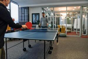 Business colleagues take a break from work to enjoy a game of table tennis, fostering teamwork and camaraderie in the workplace photo