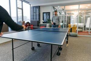 Business colleagues take a break from work to enjoy a game of table tennis, fostering teamwork and camaraderie in the workplace photo