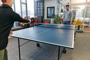 Business colleagues take a break from work to enjoy a game of table tennis, fostering teamwork and camaraderie in the workplace photo