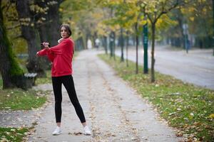 Athletic young woman taking a breath and relaxing after jogging and stretching. Woman Training and Workout Exercises On Street. photo