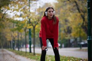 Athletic young woman taking a breath and relaxing after jogging and stretching. Woman Training and Workout Exercises On Street. photo