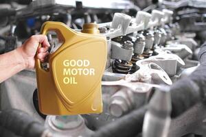 Concept of choosing good engine oil , Mechanic hand holds powerful engine oil with close up of clean engine interior in the background. photo