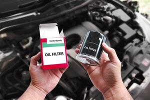 A car mechanic hand is unpacking a new oil filter to replace it. New oil filter in the hands of an car mechanic , Car maintenance concept photo