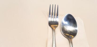 Stainless steel fork and spoon on brown napkin or towel paper setting on dinner table with copy space. Preparation, Utensil, Dining table and Shape of object concept photo