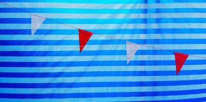 Small red and white flag hanging or isolate on line pattern of blue plastic background or wall. Target and Goal of life concept photo