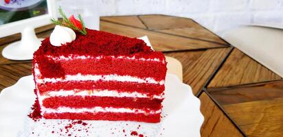 Close up Piece of Raspberry red velvet cake with Lemon cream cheese frosting on white plate putting on wooden table with copy space. Sweet dessert, Delicious and Cafe time concept. photo