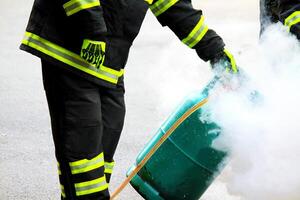 Firefighter using extinguisher and a foam cylinder to fire fighting on green gas tank burning. Rescue, Protective and Dangerous career concept. photo