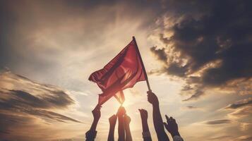 Silhouetted hands raising a flag against a dramatic sunset, symbolizing unity, resistance, and the fight for justice and equality. photo