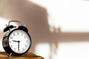 Black Vintage Alarm Clock on Wooden Table. Horizontal Photo