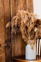 Dried Pampas Grass in Rustic Vase on Wooden Chair photo