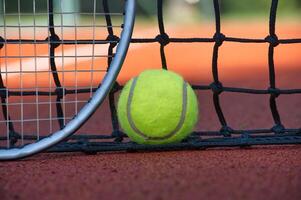 Close-up of tennis ball and racket against net on clay court photo
