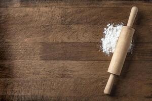 Rolling pin and flour on wooden board photo