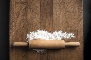 Rolling pin and flour on wooden board photo