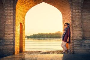 Isfahan, Iran - May 2022 - woman stand on Sio Se Pol or Bridge of 33 arches, one of the oldest bridges of Esfahan and longest bridge on Zayandeh River photo