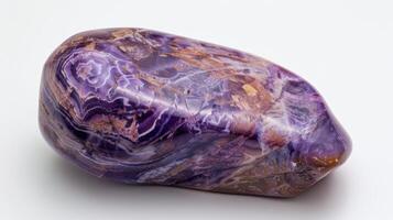 A large, vibrant purple rock is resting on a clean white surface photo