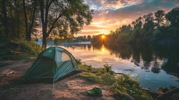 A green tent by the river during sunset surrounded by lush foliage, representing tranquility, nature, and the serene outdoor experience. photo